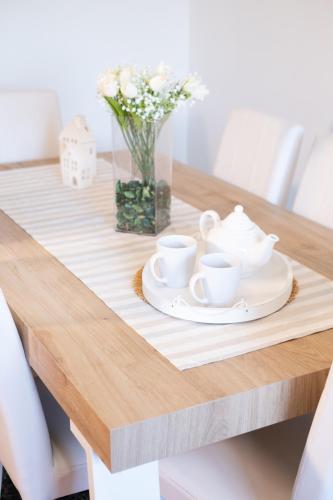 a wooden table with two tea cups and a vase of flowers at Landi 14 - Air Conditioning, Private Parking, Premium Sleep in Medicina