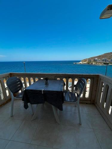 a table and chairs on a balcony overlooking the ocean at Excellent views in Marsalforn
