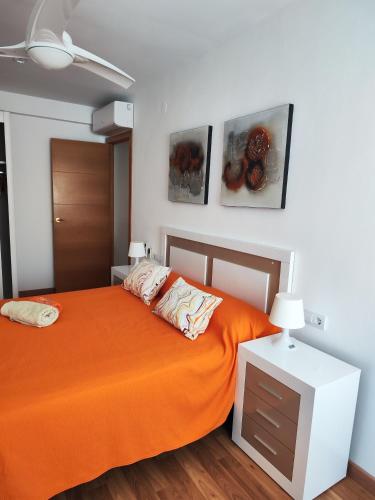 a bedroom with an orange bed and paintings on the wall at piso con estilo cerca de la playa in Cullera