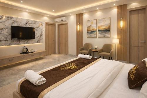 a hotel room with a large bed and a tv at Atlantiis Suites Inn By Signature Stays Near Vishwanath Temple Rathyatra in Kakarmatha