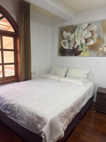 a bedroom with a white bed with a painting on the wall at The House in Tacna
