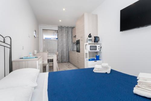 a bedroom with a blue bed and a kitchen at Molino Lounge Express 20' da Milano e Malpensa in Saronno