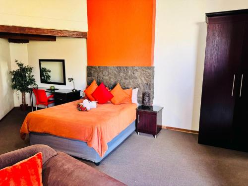 a bedroom with a bed with orange sheets and orange pillows at Kriel Windpomp Guesthouse in Aangewysd