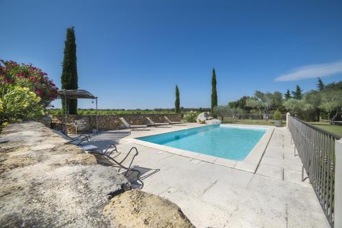 a swimming pool with chairs next to a stone wall at Le Petit Mas - Piscine Clim in Grillon