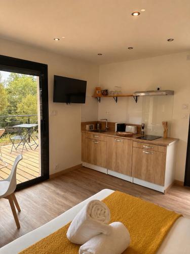 a room with a kitchen and a balcony with a table at Lo Coustil in Saint-Martin-Labouval