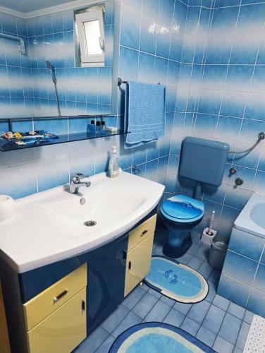 a blue bathroom with a sink and a toilet at Apartmani Srebrenik in Srebrenik