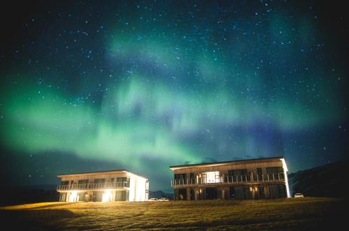 two buildings under the northern lights in the sky at Black Beach Suites in Vík