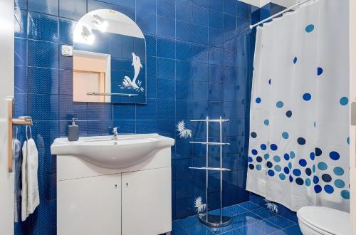 a blue tiled bathroom with a sink and a shower at Apartamento Village Elvas in Vilamoura