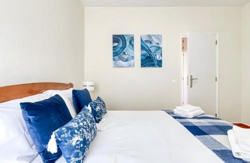 a bedroom with a large bed with blue pillows at Apartamento Village Elvas in Vilamoura
