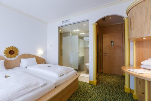 a bedroom with a large bed and a bathroom at Das-Schmidt Privathotel in Mörbisch am See