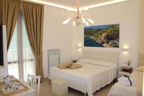 a white bedroom with two beds and a window at Villa Miriam in Gragnano