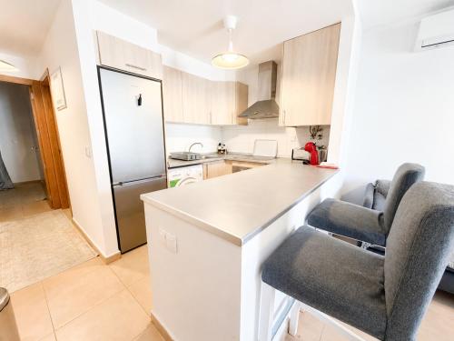 a kitchen with a white counter and two chairs in it at Condado de Alhama 5 SV29 in Alhama de Murcia