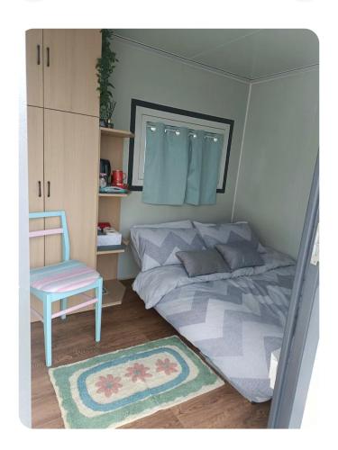 a bedroom with a bed and a chair and a rug at Róisín's Country cabin in Milltown Malbay