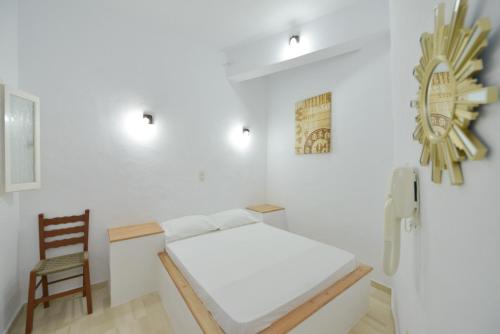 a white room with a bed and a chair at Windmill Villas in Artemonas