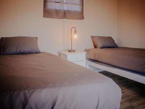 a bedroom with two beds and a lamp on a night stand at Karoo 62 Bush Motel in Ladismith