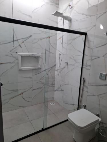 a bathroom with a toilet and a glass shower at casa da Roberta SJB capitólio in São José da Barra