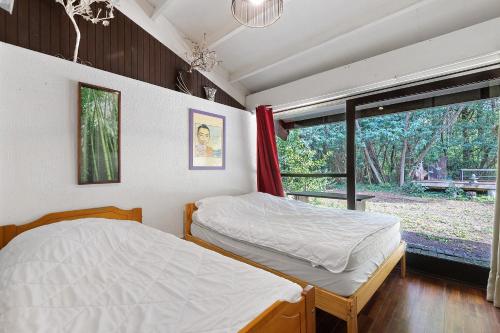 two beds in a room with a window at Maison de vacances Namasté in Mérignac