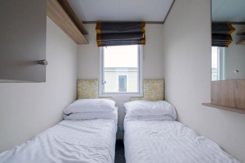 two beds in a small room with a window at Cockerham Sands Holiday Park in Cockerham