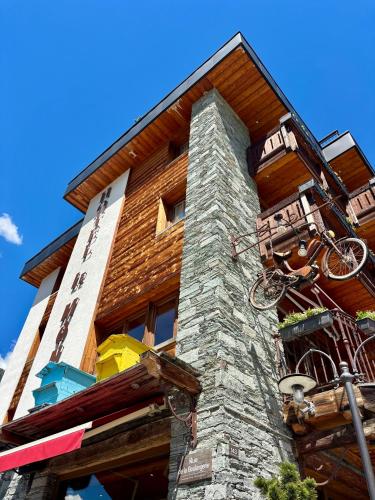 a building with a stone tower with a bike on it at Hôtel Le Monal in Sainte-Foy-Tarentaise