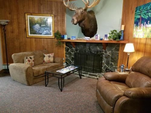 a living room with a fireplace with a deer head on the wall at Soldotna Inn in Soldotna