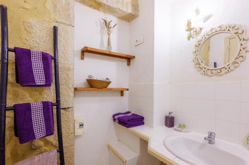 a bathroom with a sink and a mirror and purple towels at Chez Bacchus - Chambres in Gras