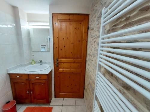 a bathroom with a wooden door and a sink at Le Liboureau in Saint-Jean-de-Vaux
