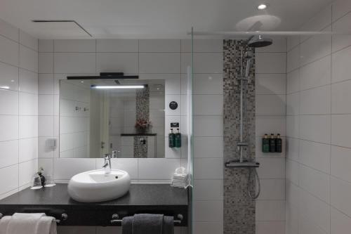 a bathroom with a sink and a shower with a mirror at Clarion Hotel Gillet in Uppsala
