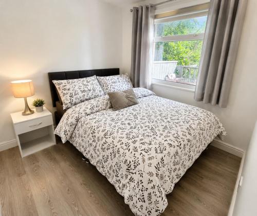 a bed with a black and white comforter and a window at 18 river view chalet-Glan Gwna Holiday Park in Caernarfon