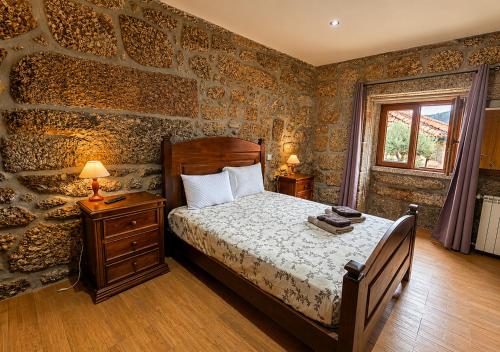 a bedroom with a bed and a stone wall at Casa da Bia - Gerês in Terras de Bouro