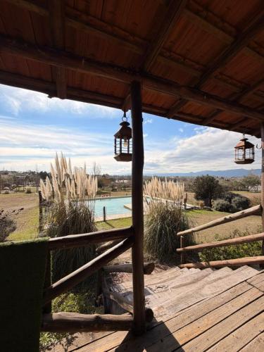 a wooden porch with two lights and a pool at Cabaña de campo in Tanti