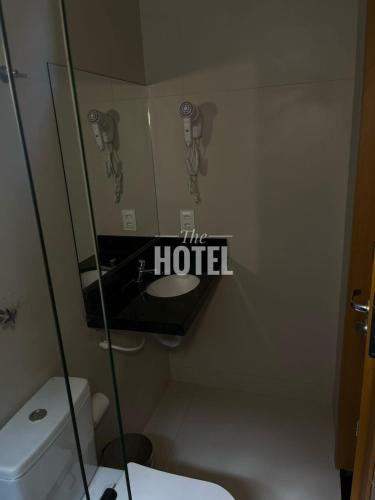a bathroom with a toilet and the hotel sign on the wall at The Hotel in Teresina