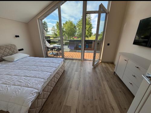 a bedroom with a bed and a large window at Kotedžas su baseinu ir pirtimi in Palanga