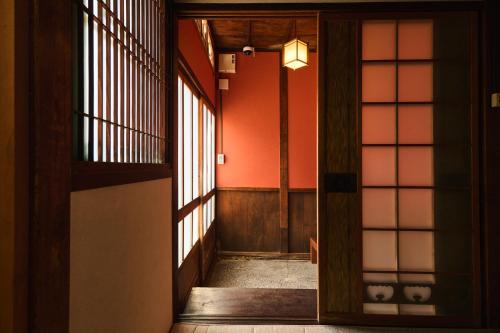 a hallway with orange walls and an open door at Kanazawa Machiya Kasaichi - Entire House Free Parking in Kanazawa