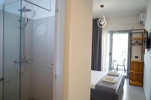 a bathroom with a shower and a bed and a glass door at Maor Hotel in Vlorë