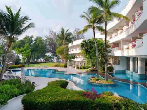 a resort with a swimming pool and palm trees at Novotel Rayong Rim Pae Resort in Klaeng