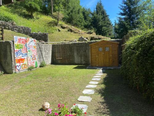 a garden with a wooden shed and a wall with graffiti at Maison au Soleil in Valtournenche