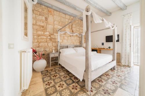 a bedroom with a bed and a stone wall at Antico Mondo Rooms & Suites in Polignano a Mare
