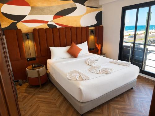 a bedroom with a large white bed with a painting on the wall at Oceana Mazagan Suites Hôtel in El Jadida
