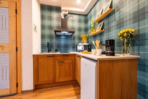a kitchen with wooden cabinets and green tiles at Apartamenty pod Góralskim Niebem in Gliczarów Górny