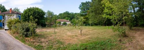 a field with trees and a house and a road at Lacour in Augignac