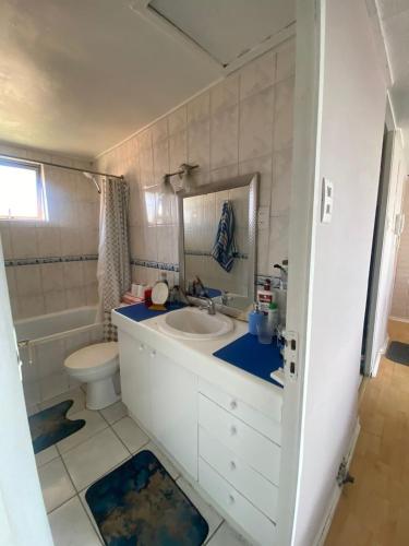 a bathroom with a sink and a toilet and a mirror at Comfortable apartment steps from Portal Belloto in Quilpué