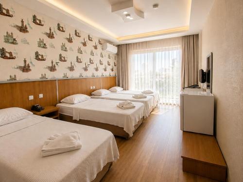 a hotel room with three beds and a television at mood beach hotel in Didim
