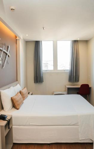 a large white bed in a room with windows at Easy Hotel Cachoeiro de Itapemirim by Atlantica in Cachoeiro de Itapemirim