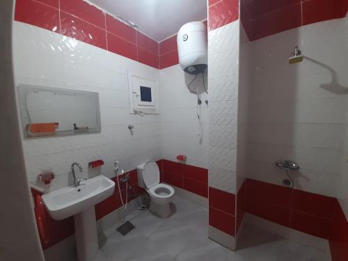 a red and white bathroom with a toilet and a sink at The Blue House in Safaga