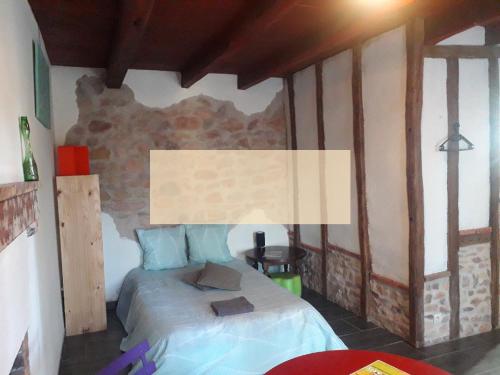 a bedroom with a bed and a stone wall at Odyssée auvergne in Vallon-en-Sully