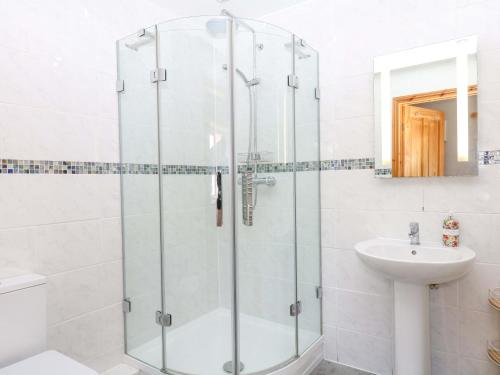 a bathroom with a glass shower and a sink at The Milk Shed in Plymtree