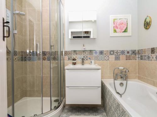 a bathroom with a shower and a tub and a sink at Mei's Cottage in Exeter
