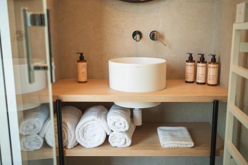 a bathroom with a sink and towels on a shelf at Domaine des Grands Sables, Île Groix - Handwritten Collection in Groix
