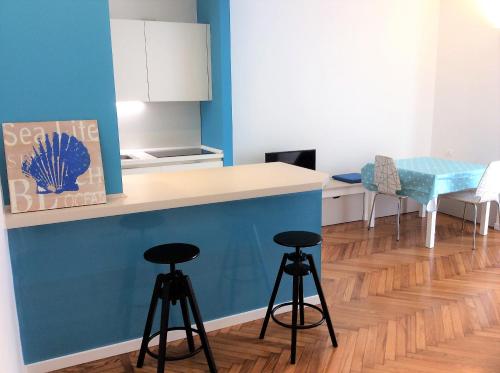 サンレモにあるAppartamento Mare 103のキッチン(スツール付)、青い壁のカウンター