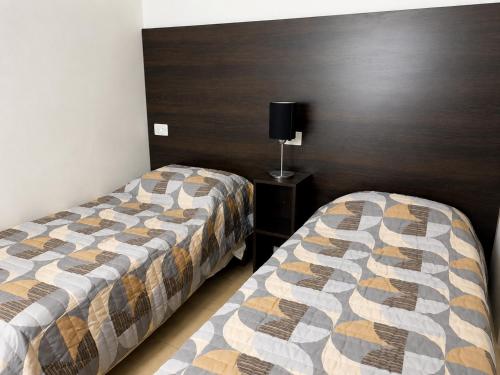 a room with two beds and a table with a lamp at Norita Alquiler Temporal - Departamento in La Rioja